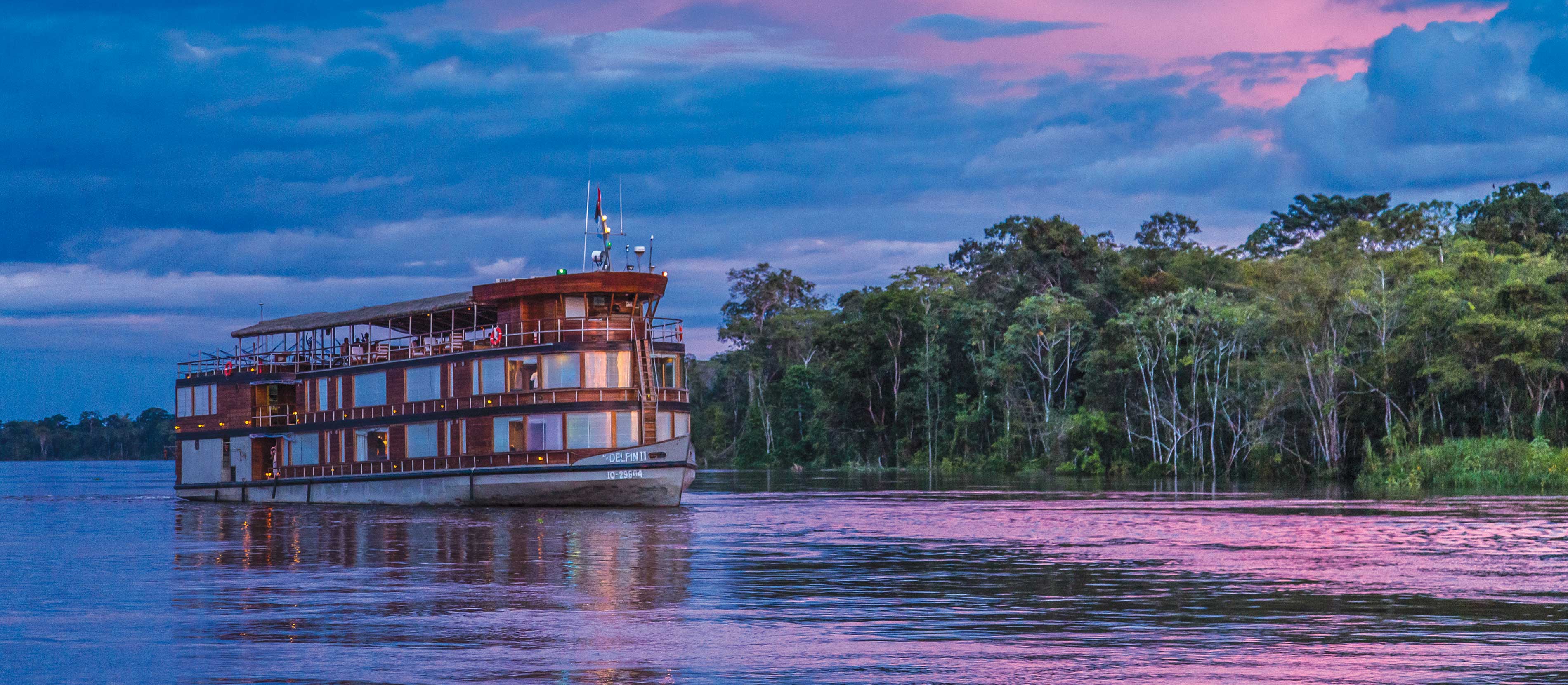 A small boat navigating a winding river in the Amazon rainforest.